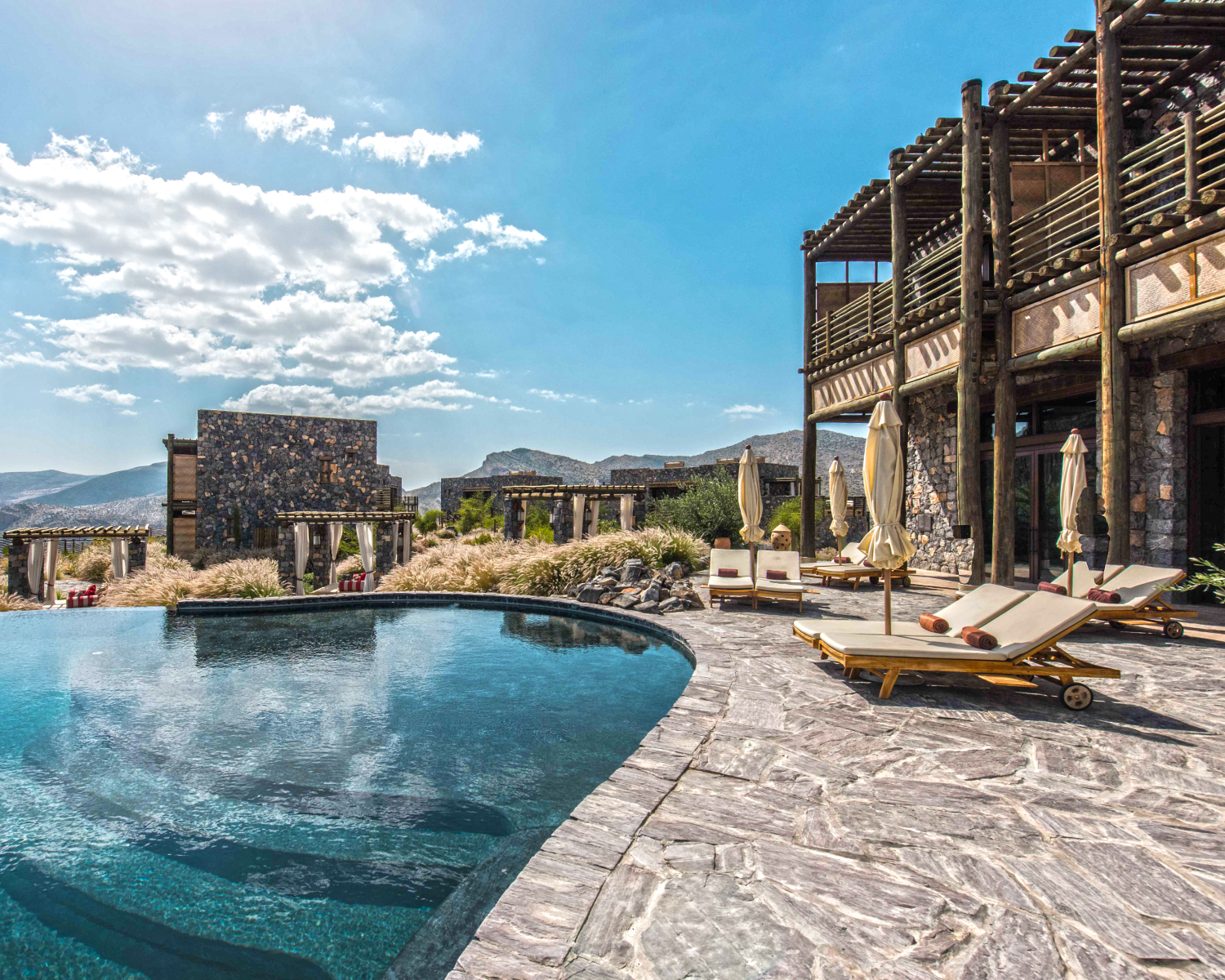 Pool and hotel exterior with mountains in the backdrop