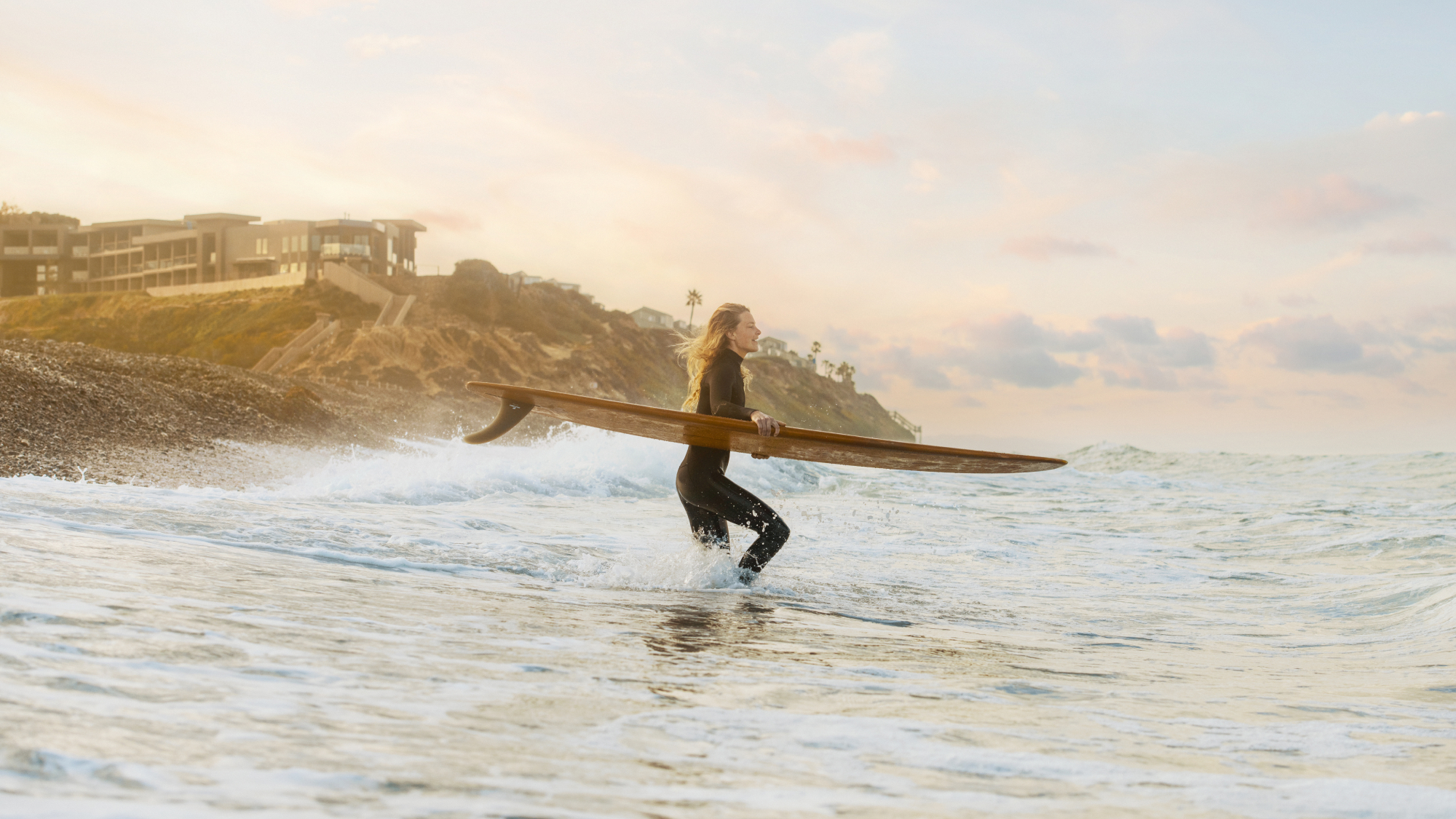 woman in the ocean carrying a surf board