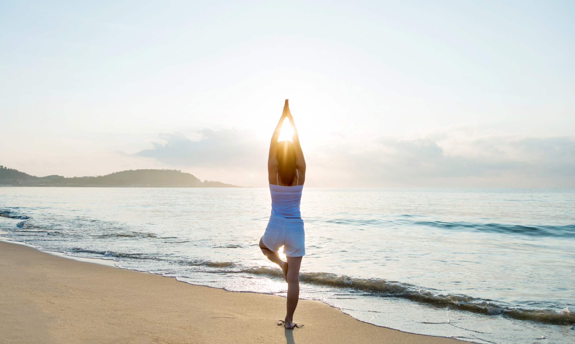 woman doing a yoga pose on the beach