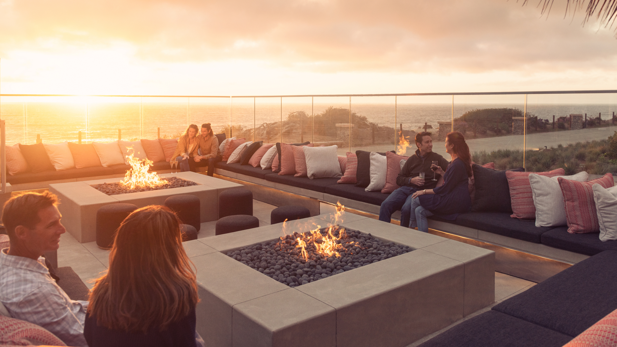 couples sitting by the fire pit at sunset