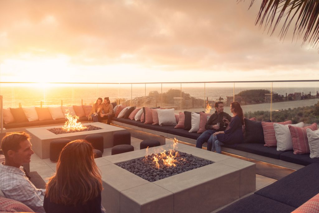 couples sitting by the fire pit at sunset