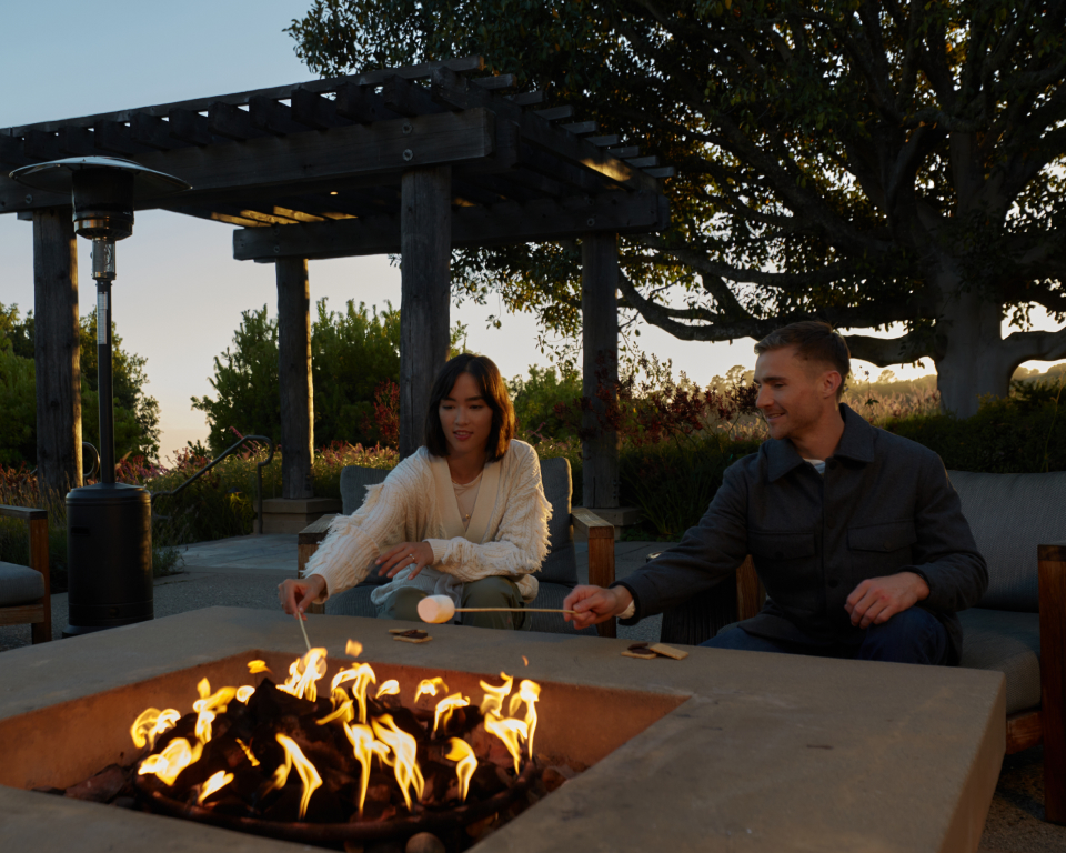 couple sitting by fireplace melting smores