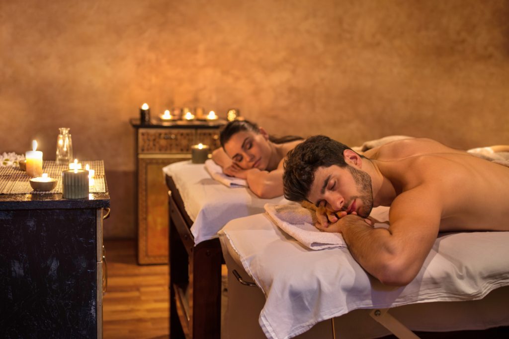 Man and woman lying on massage beds on their front sides