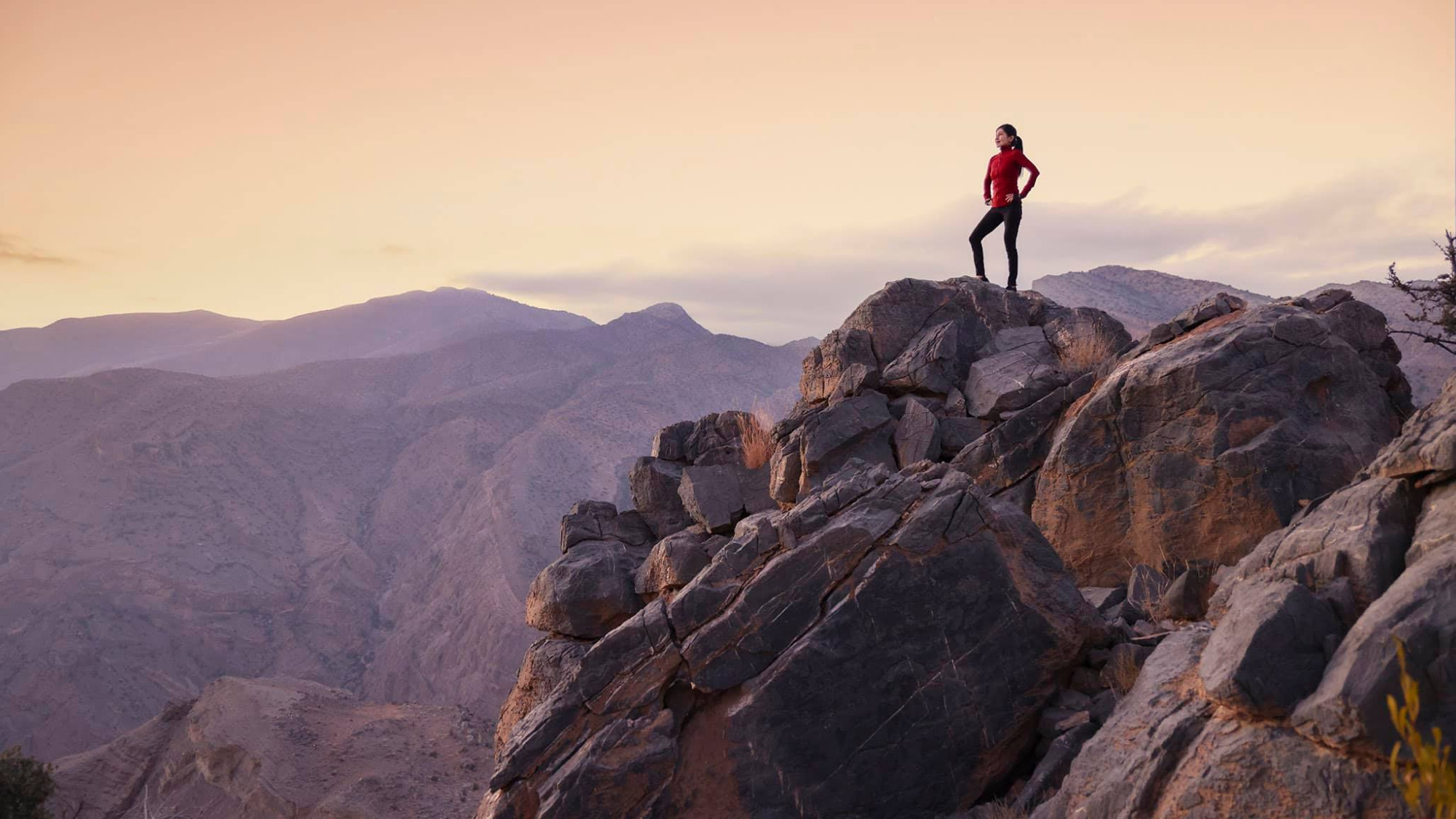 person on the top of a cliff at sunset