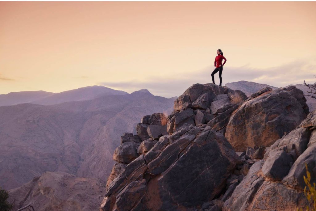 person on the top of a cliff at sunset