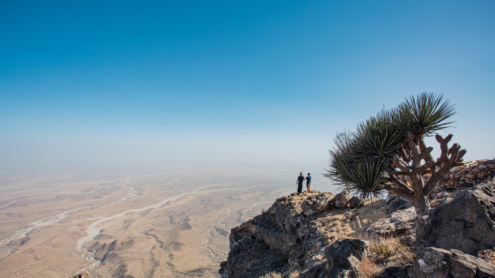 view of two people standing at the top of mountain