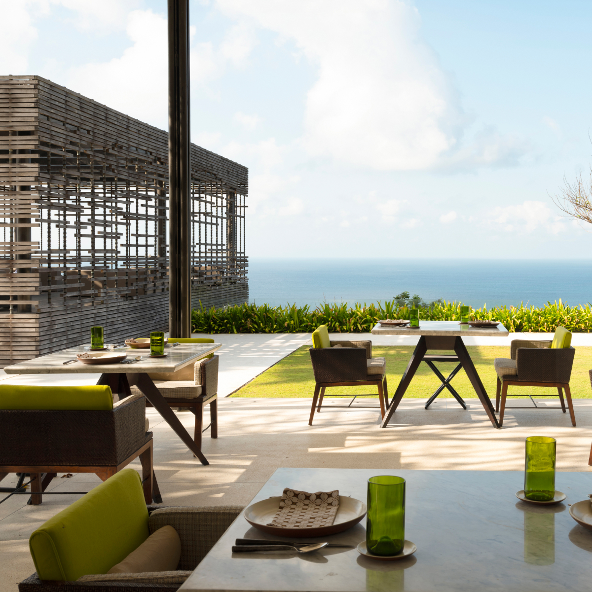 Restaurant tables and chairs on a covered patio overlook the ocean