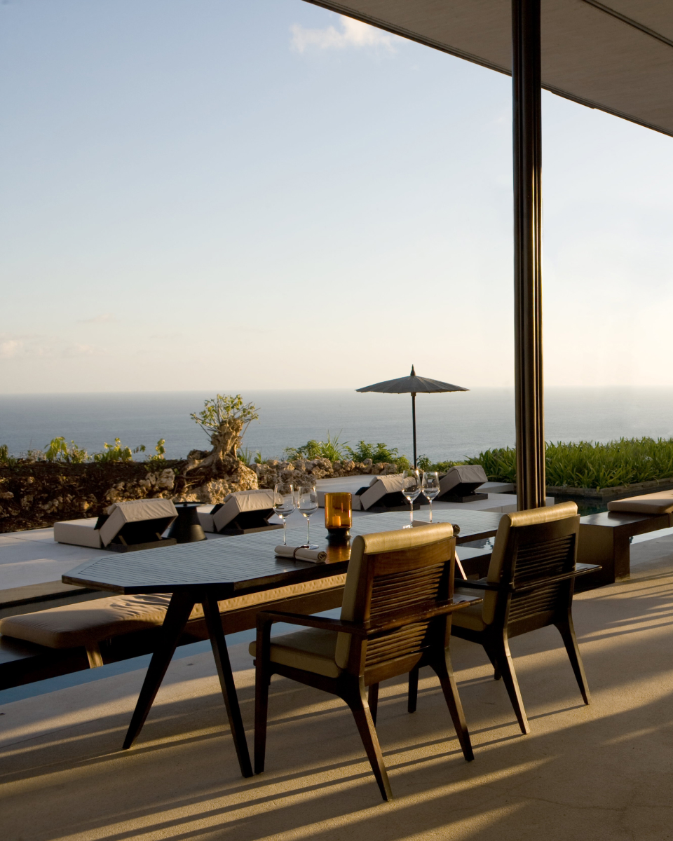Restaurant table with two chairs overlooking lounge chairs with ocean view