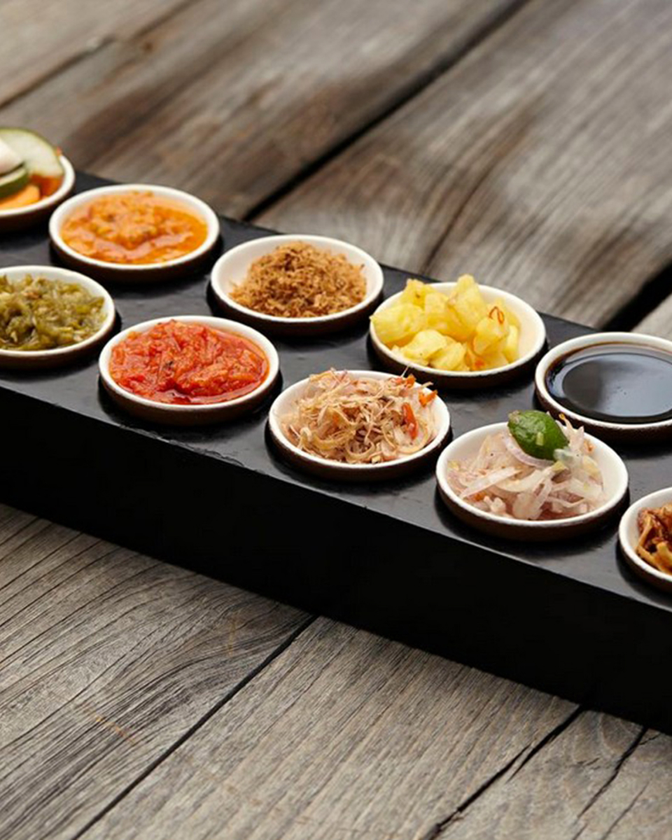 Small bowls on a serving tray showing various dips and garnishes for food