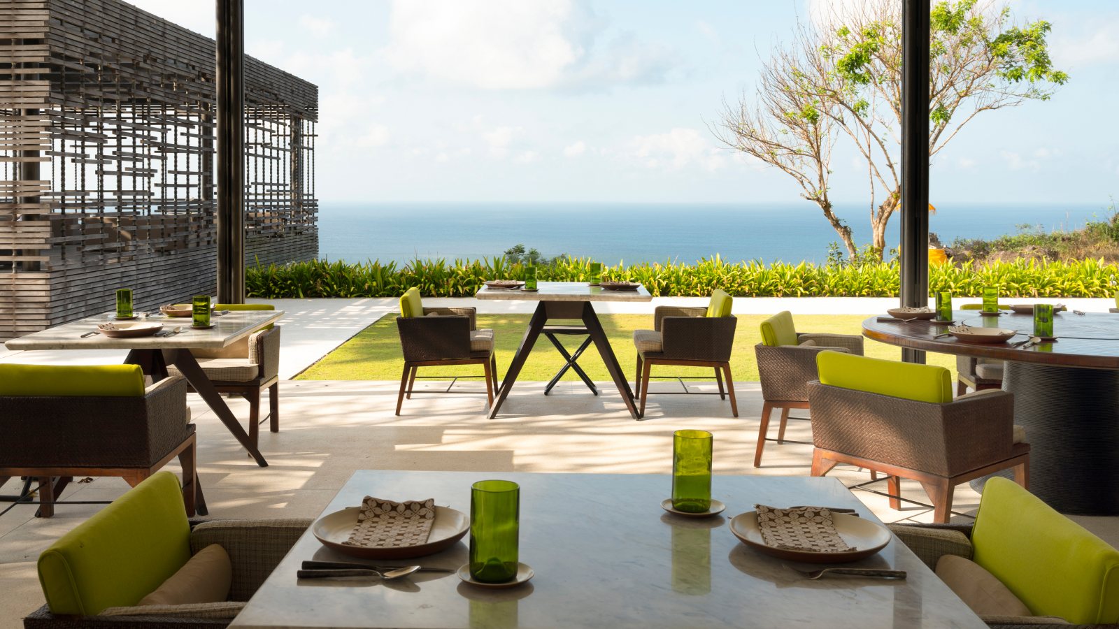 Restaurant tables and chairs on a covered patio overlook the ocean