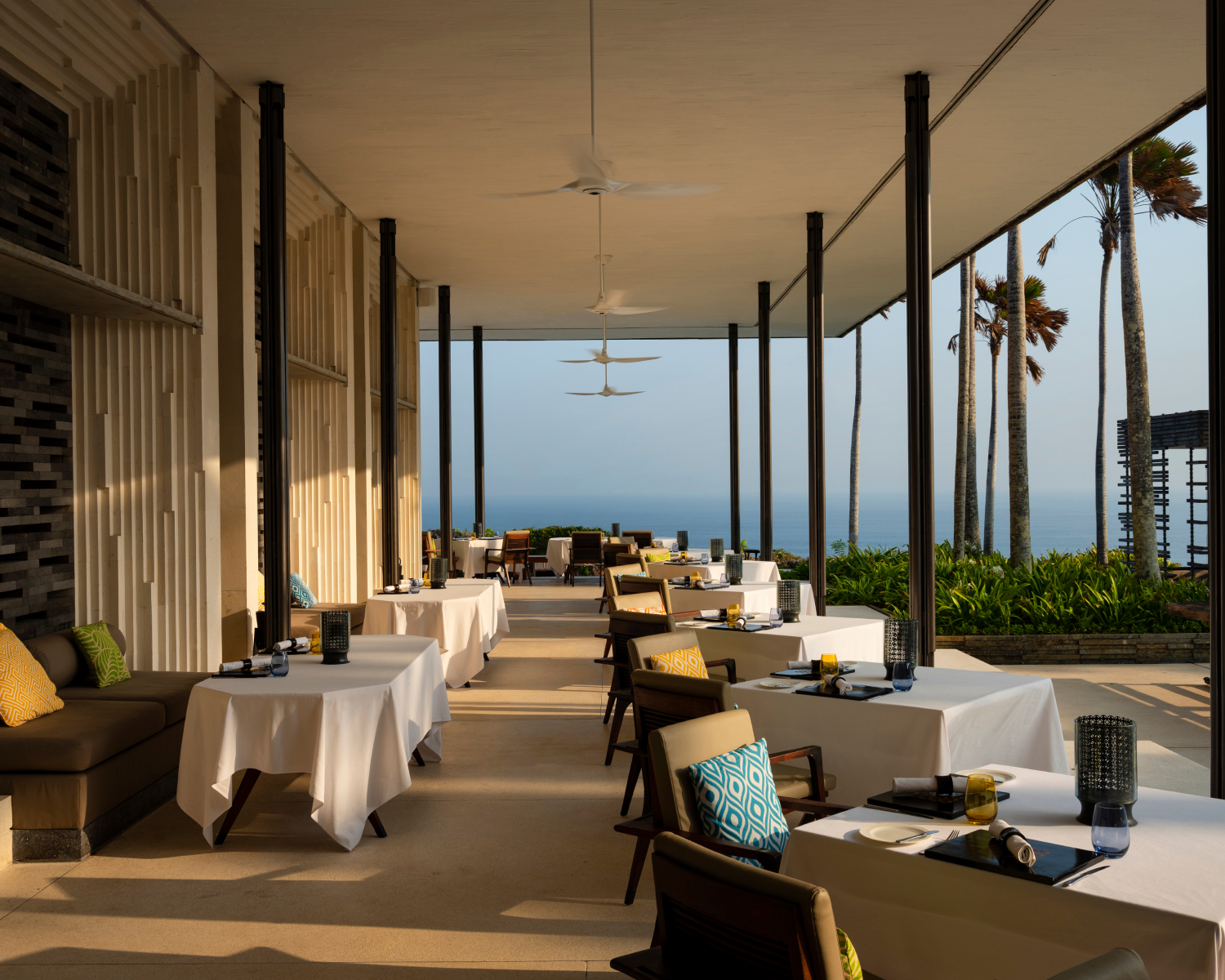 Restaurant patio with tables and chairs with ocean view in the background.