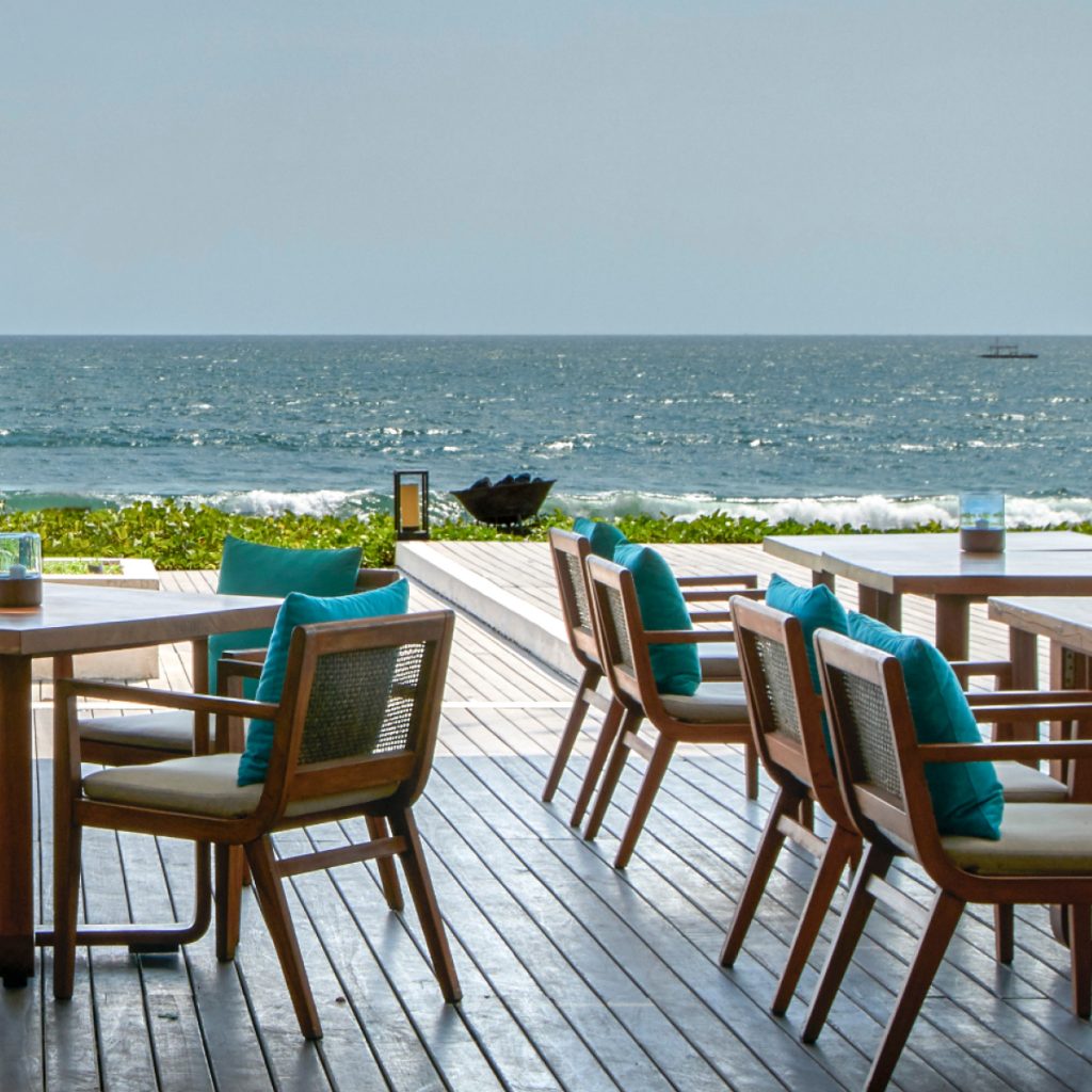 wooden chairs with blue pillows by the ocean