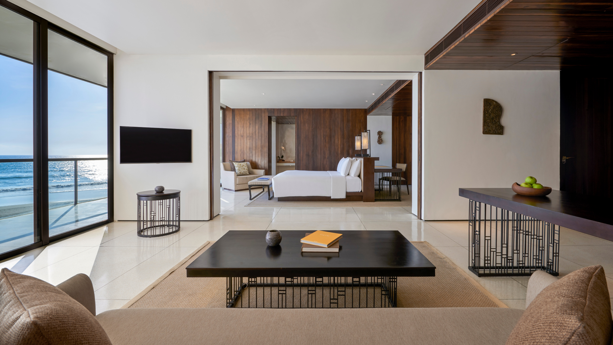 Living room area in foreground with open doors to bedroom.