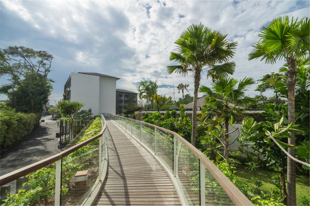 Walking bridge with palm trees and hotel in background