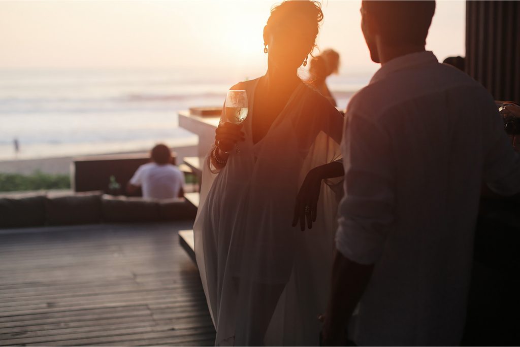 Two people standing outside at dusk with drinks in hand