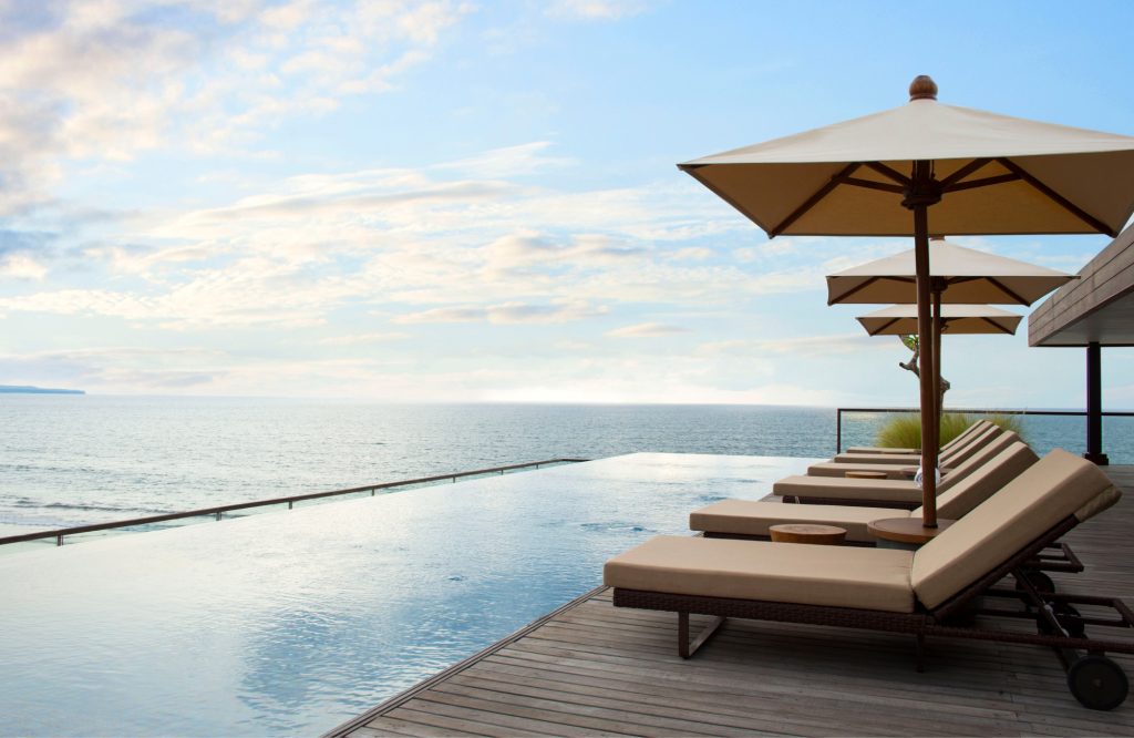 Infinity pool overlooking the ocean with lounge chairs.