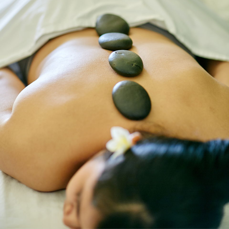 Woman lying on massage bed with stones down her spine