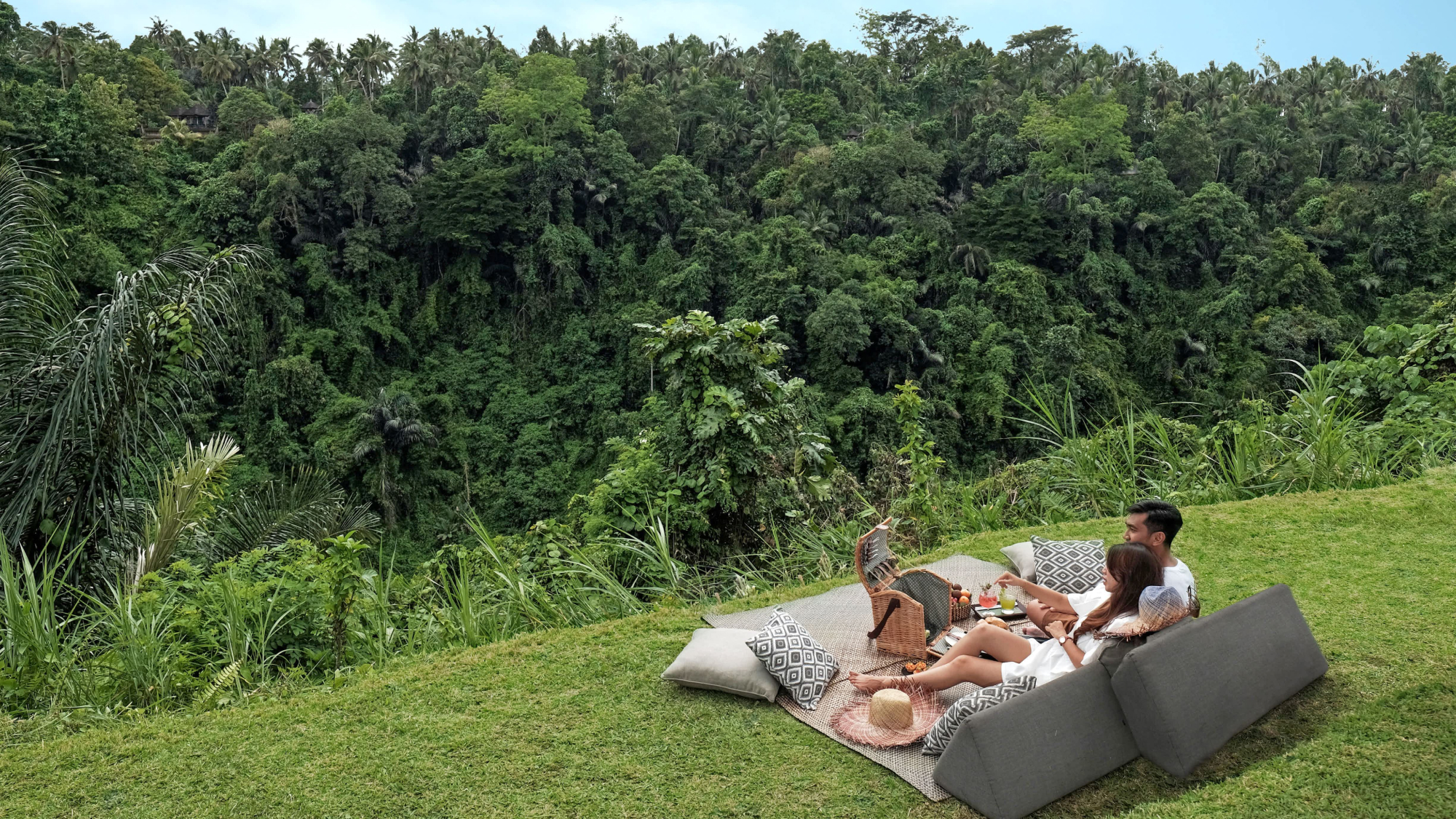 couple laying on a hill having a picnic looking into the jungle