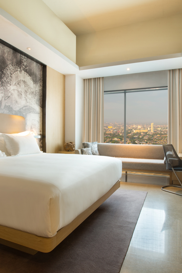 interior hotel room with large bed and view of city